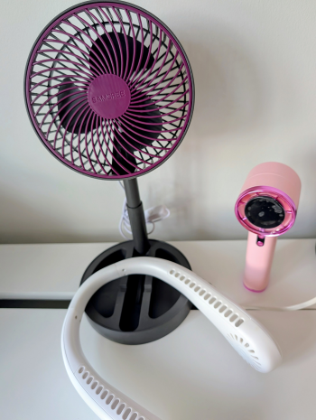 Purple circular desk fan with a protective grid and dark blades on a stand, viewed at an angle from the left.